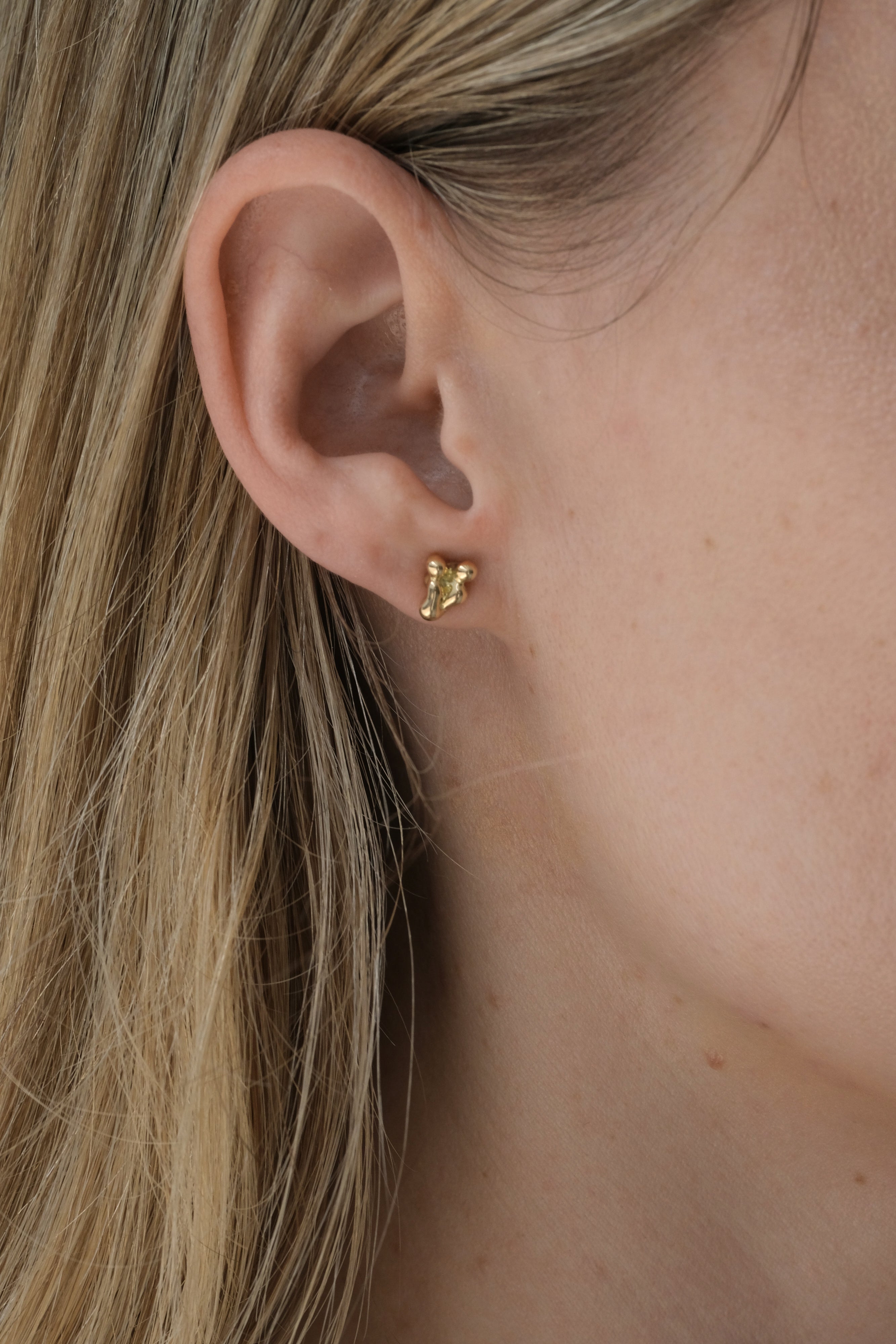 Handmade ethical earrings in recycled yellow gold, showcasing a unique design, worn by a model in Basel, Switzerland.