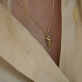 Handmade unique necklace in 18k recycled gold worn on a light beige blouse, showcasing ethical and sustainable jewelry.