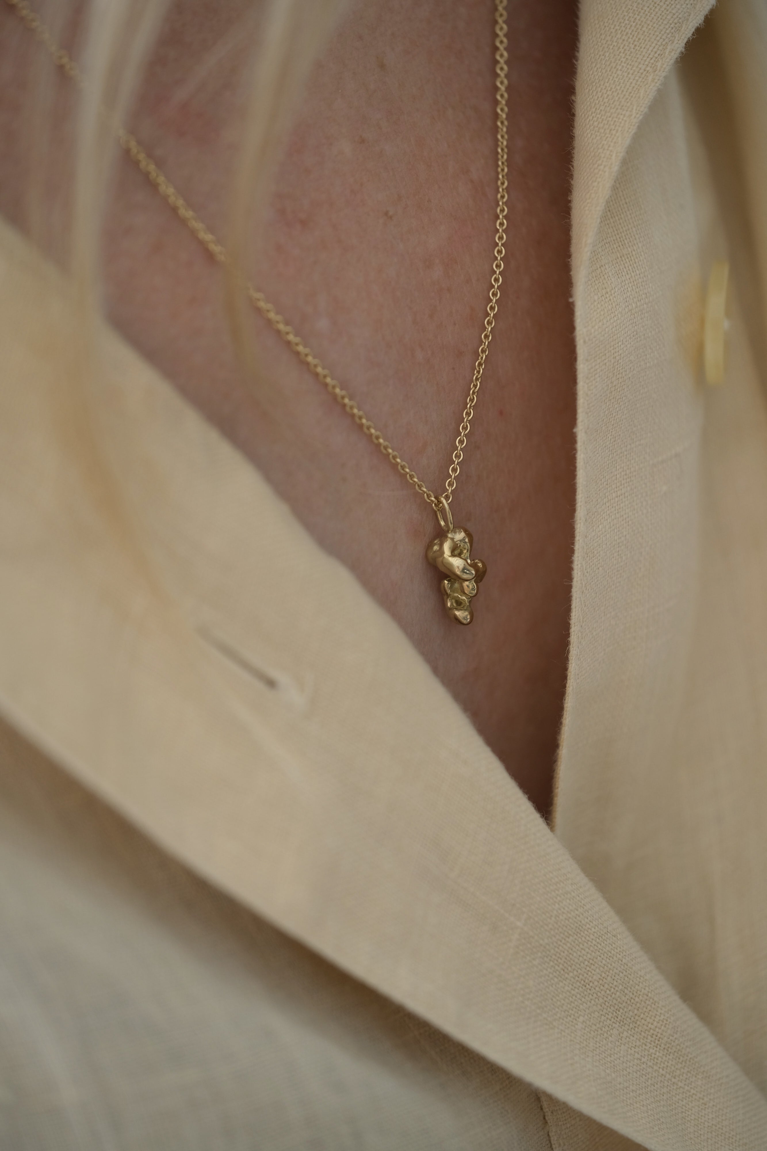 Handmade unique necklace in 18k recycled gold worn on a light beige blouse, showcasing ethical and sustainable jewelry.