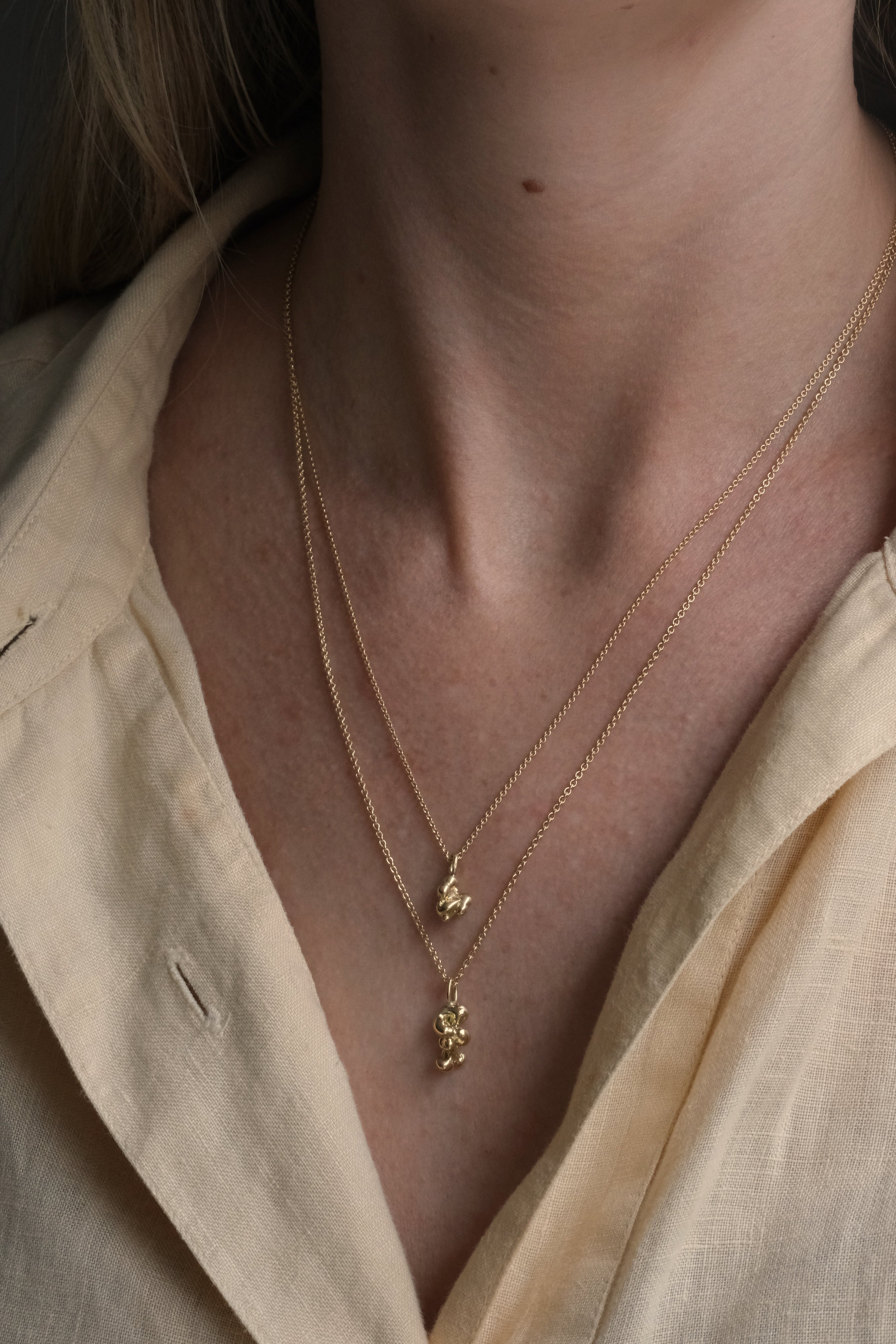 Two layered necklaces in recycled gold showcased on a model, embodying ethical and sustainable jewelry from Basel, Switzerland.