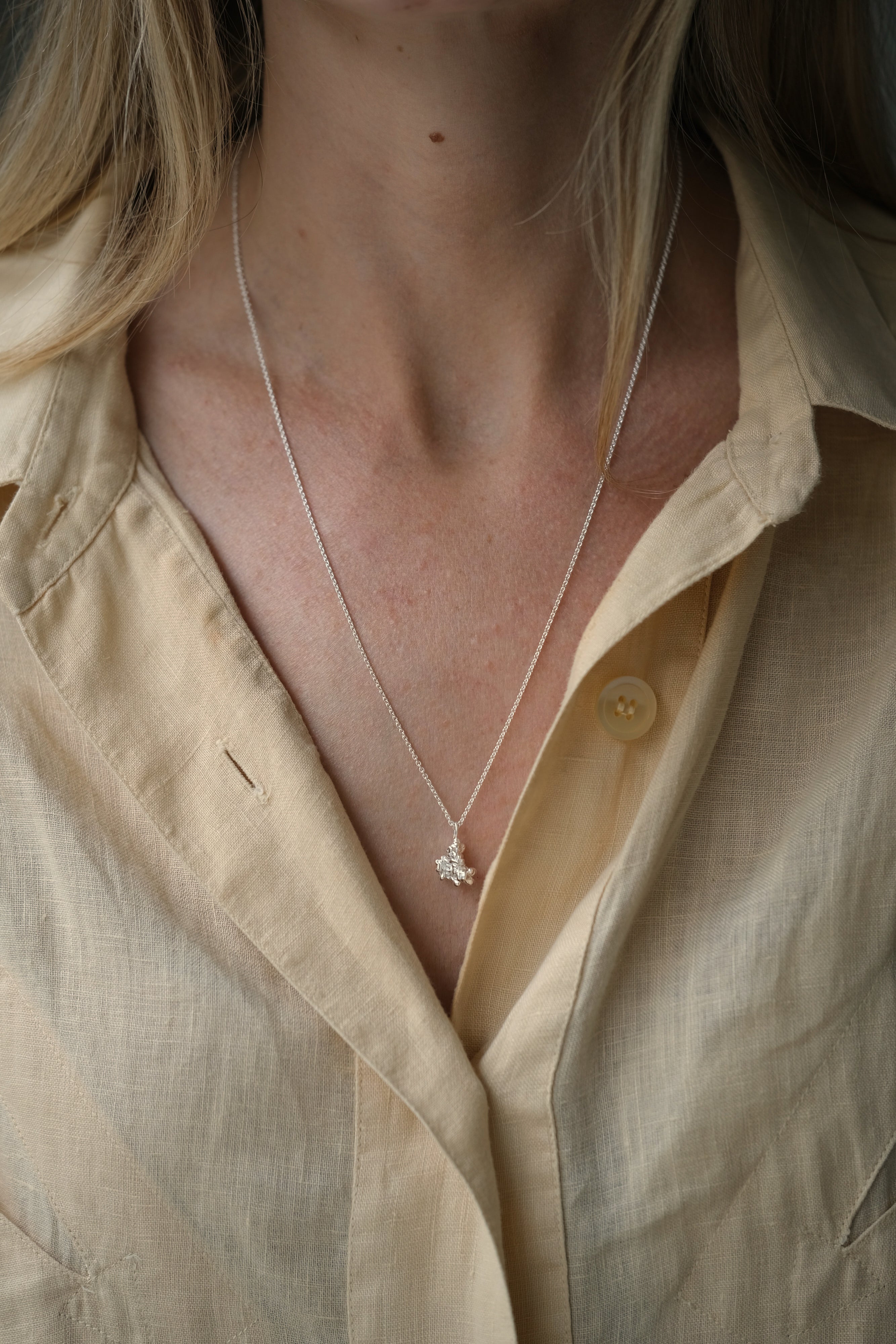Handmade DROP 03 necklace in 925 recycled silver, worn with a light yellow shirt, showcasing ethical jewelry craftsmanship.