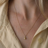 close-up of a person wearing the DROP 03 necklace made of recycled yellow gold, highlighting its unique design and shine.