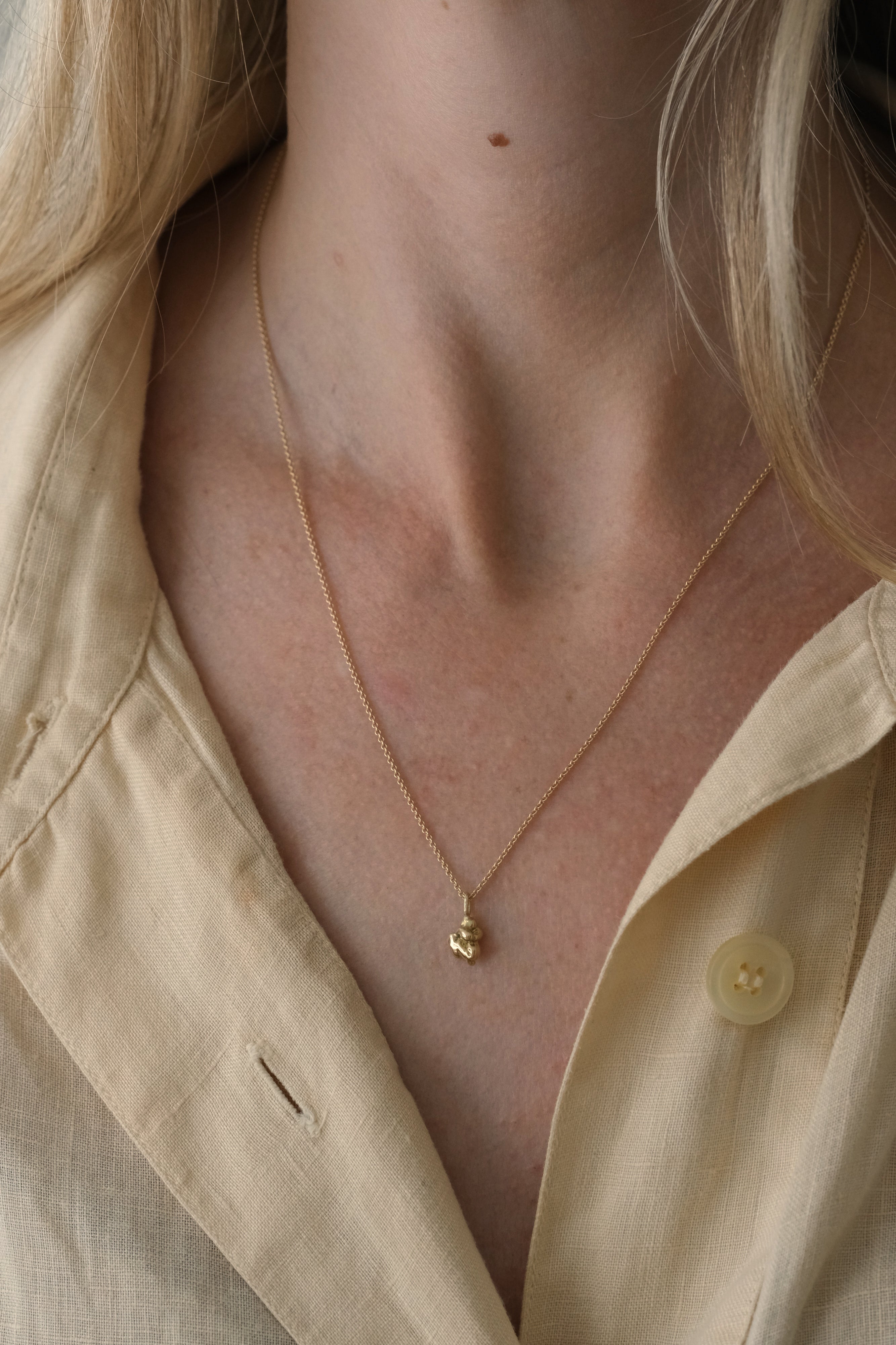 close-up of a person wearing the DROP 03 necklace made of recycled yellow gold, highlighting its unique design and shine.