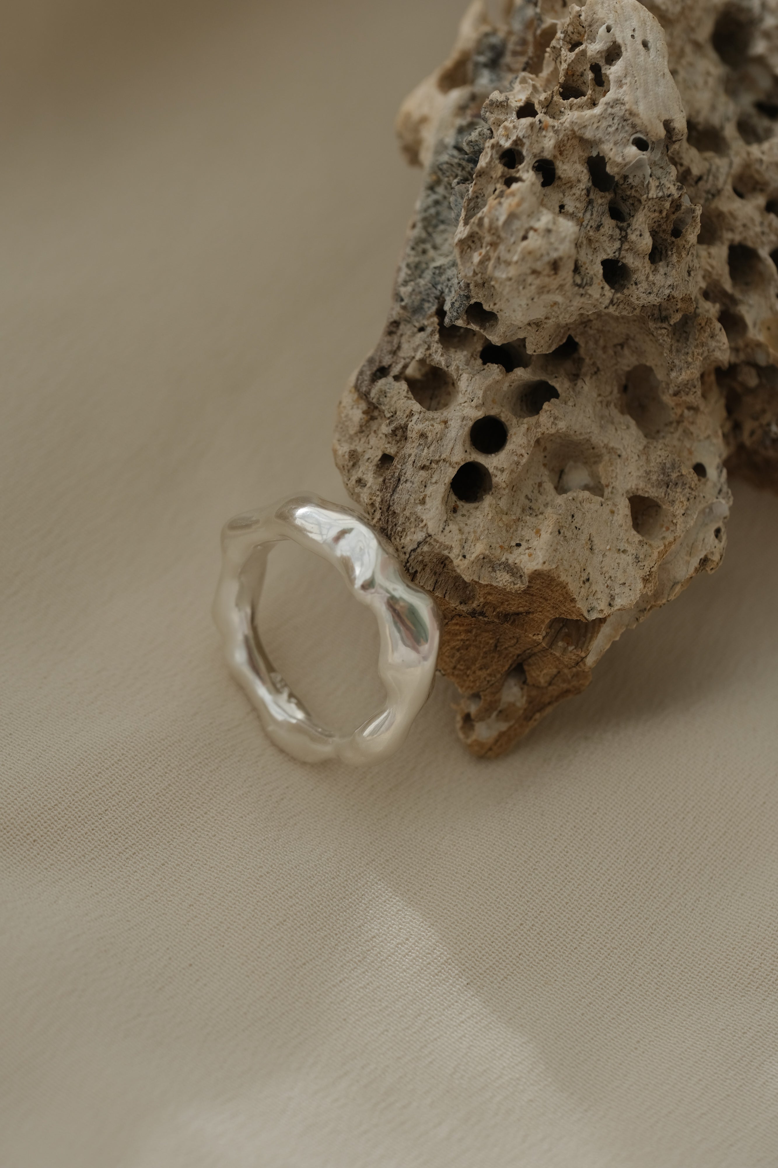 Handmade sustainable silver ring resting on natural texture, unique jewelry from Basel, Switzerland.