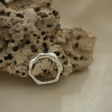 Handmade ring DROP 03 in 925 recycled silver, showcasing a natural shiny finish on textured stone background.