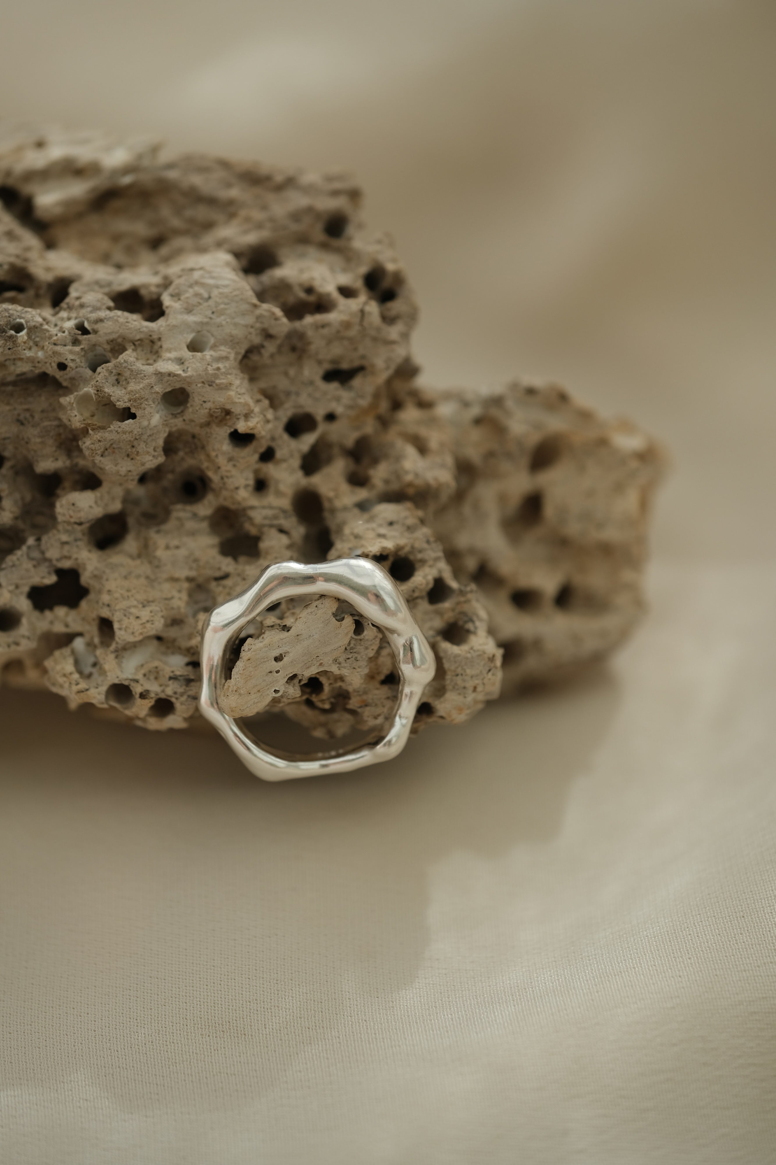 Handmade ring DROP 03 in 925 recycled silver, showcasing a natural shiny finish on textured stone background.