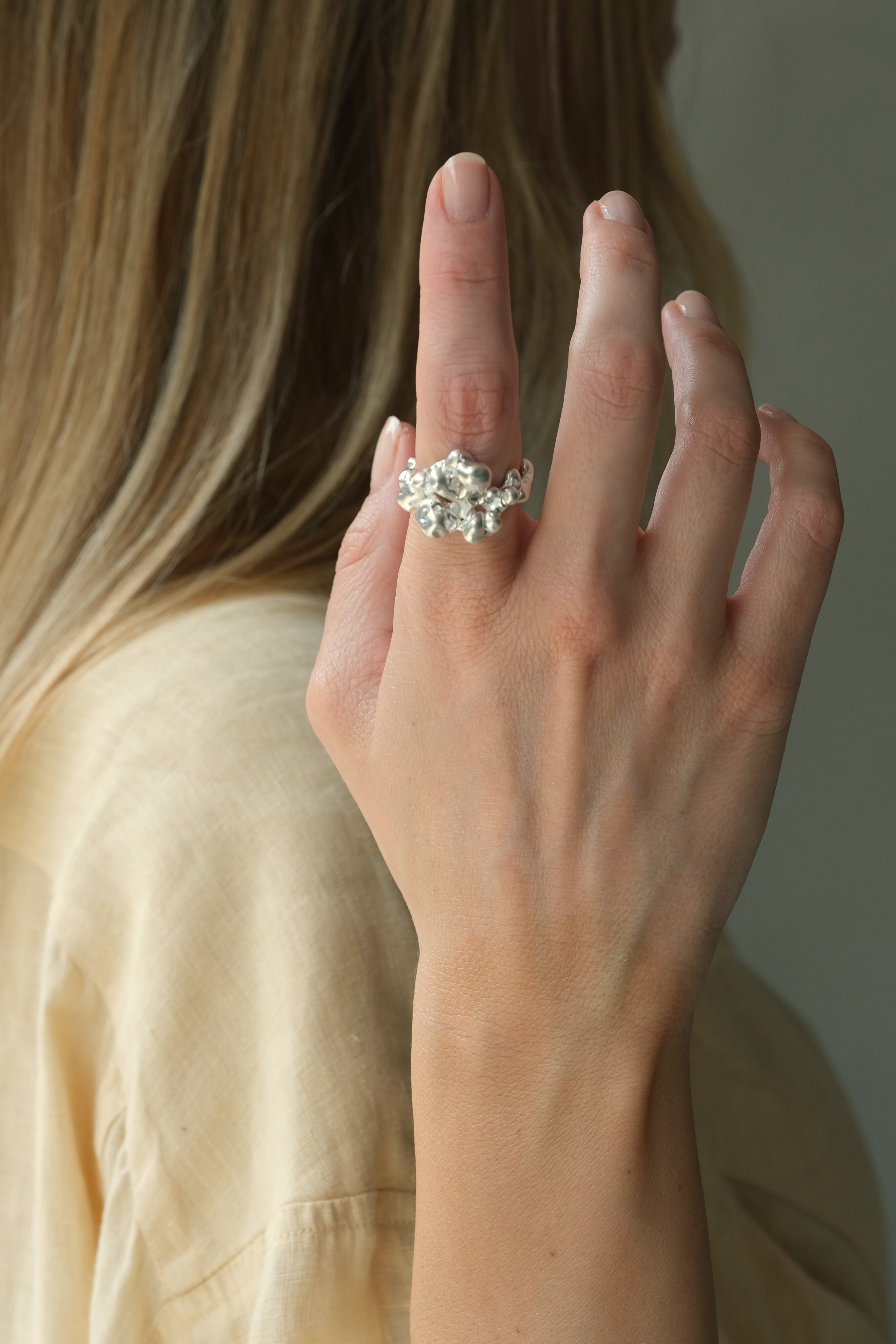 A woman wearing a handmade DROP 03 ring crafted from 925 recycled silver, showcasing unique, ethical jewelry.