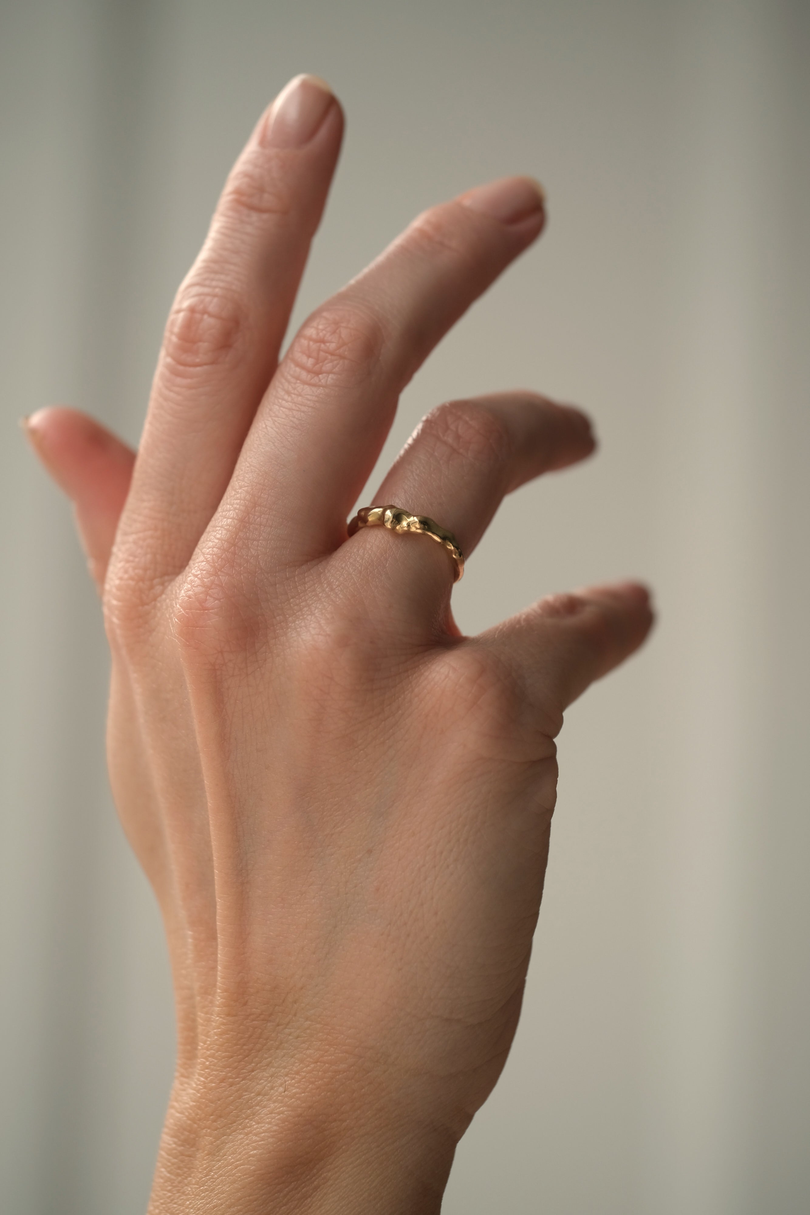 Hand wearing DROP 03 ring in recycled yellow gold, showcasing ethical and sustainable handmade jewelry from Basel Switzerland.