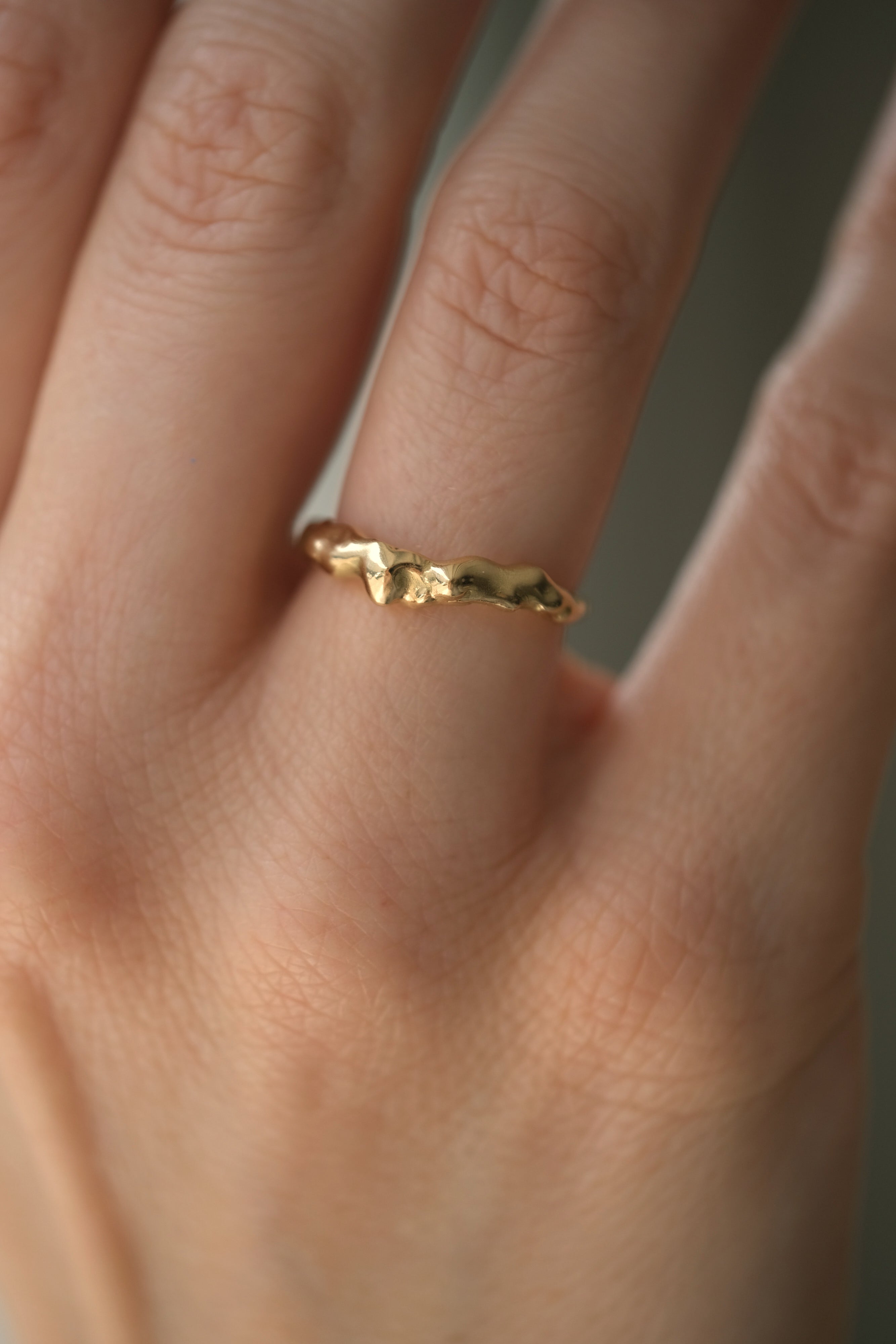 Handmade DROP 03 ring in recycled yellow gold on a finger, showcasing unique ethical and sustainable jewelry from Basel.
