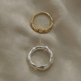 Handmade ethical and sustainable jewelry rings in gold and silver on soft fabric backdrop.
