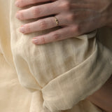 Hand model wearing DROP 03 ring two made of recycled yellow gold, showcasing ethical handmade jewelry in Basel.