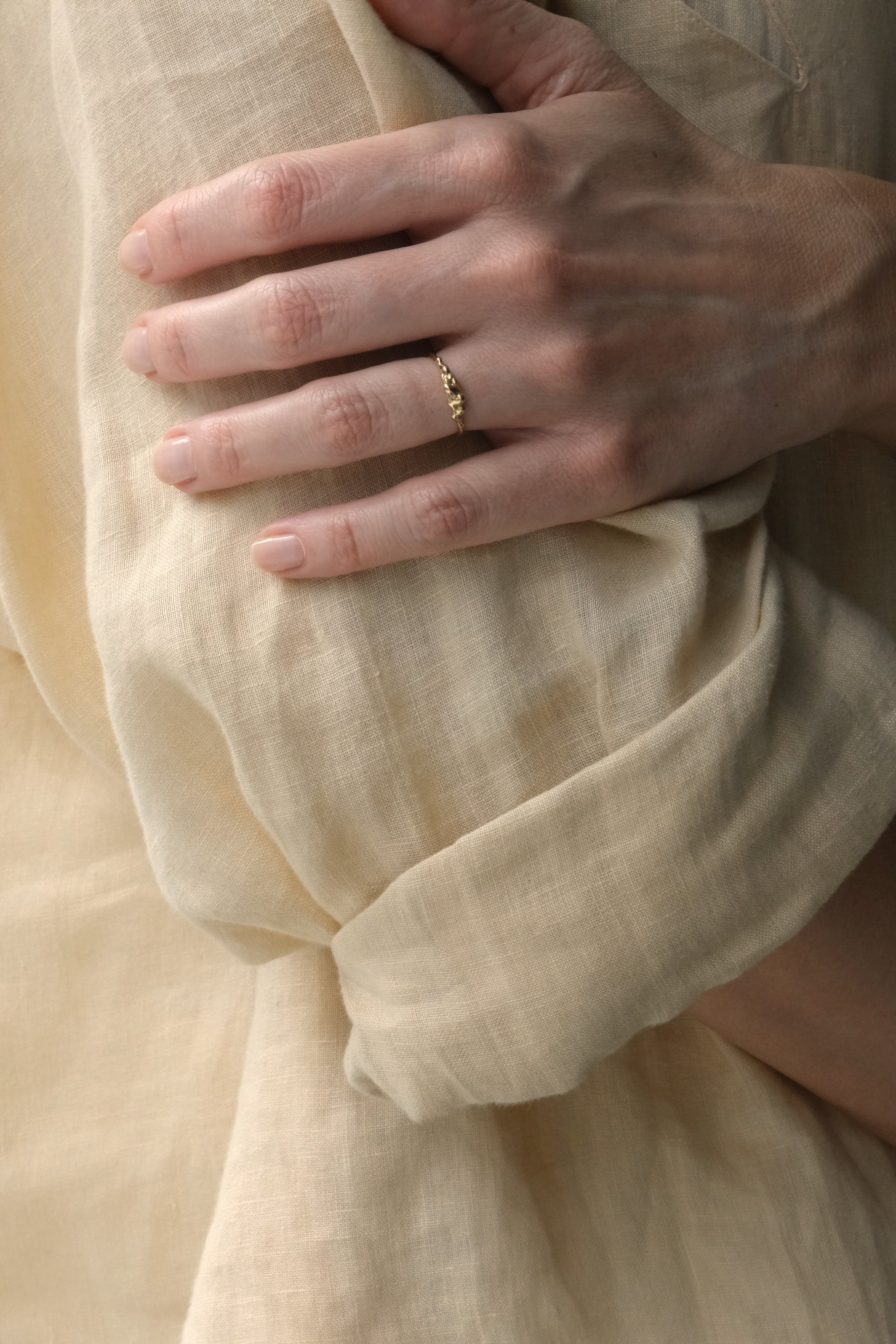 Hand model wearing DROP 03 ring two made of recycled yellow gold, showcasing ethical handmade jewelry in Basel.