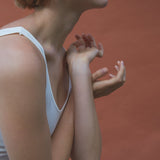 Model wearing AROYO small earrings, showcasing handmade ethical jewelry with a semi-matte finish against a warm backdrop.