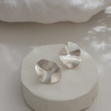 Handmade AROYO small earrings made of recycled silver in a semi-matte finish, displayed on a minimalist stand.