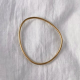 LOON bangle made of 18k gold-plated recycled silver, showcasing a handmade, semi-shiny finish on a white linen background.