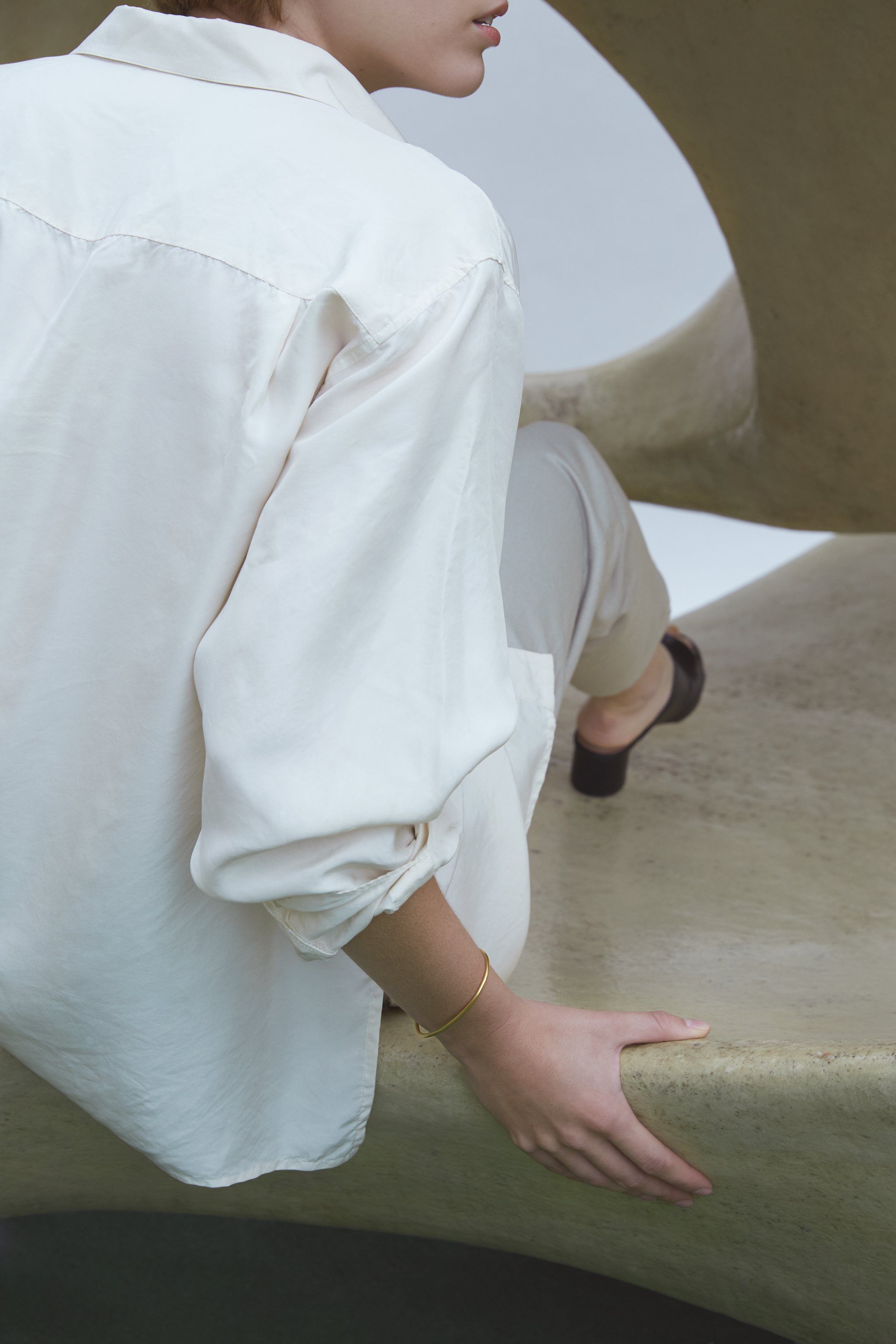Woman wearing a LOON bangle, showcasing ethical and sustainable handmade jewelry in a minimalist setting.