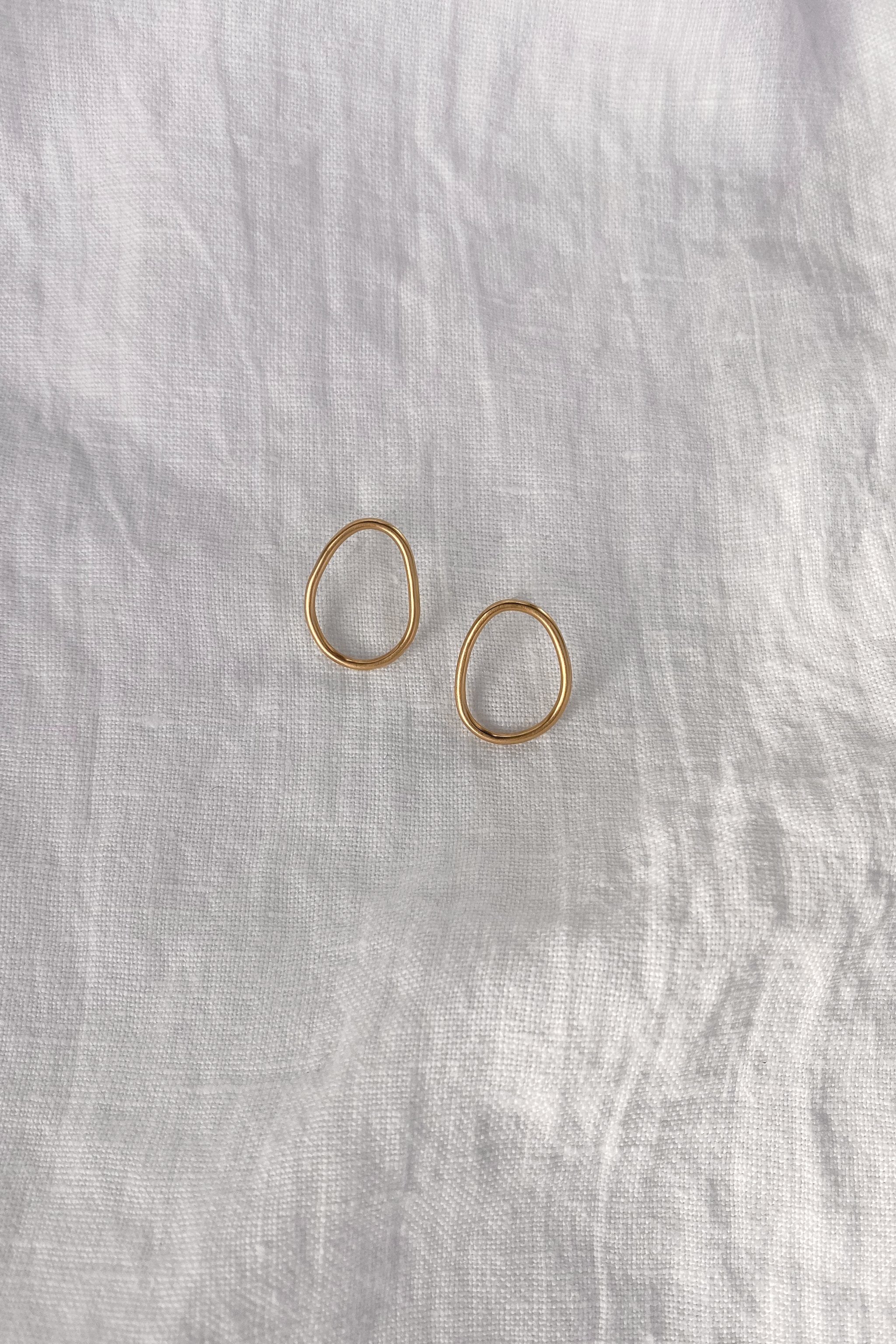 LOON small earrings in 18k gold-plated recycled silver, handmade ethical jewelry on a light fabric background.