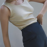Model wearing a ribbed beige tank top paired with high-waisted navy trousers, showcasing a trendy outfit.