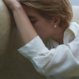 Model wearing ONOA earrings, showcasing ethical jewelry with a semi-matte finish in a serene setting.