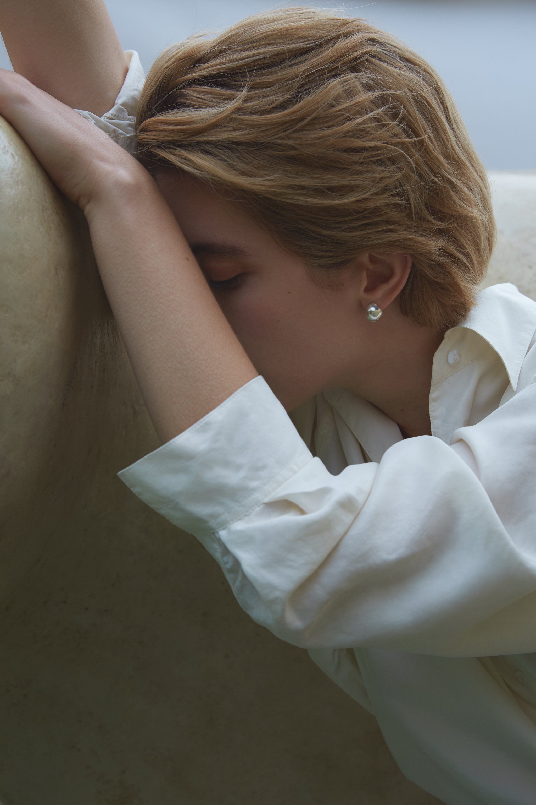Model wearing ONOA earrings, showcasing ethical jewelry with a semi-matte finish in a serene setting.
