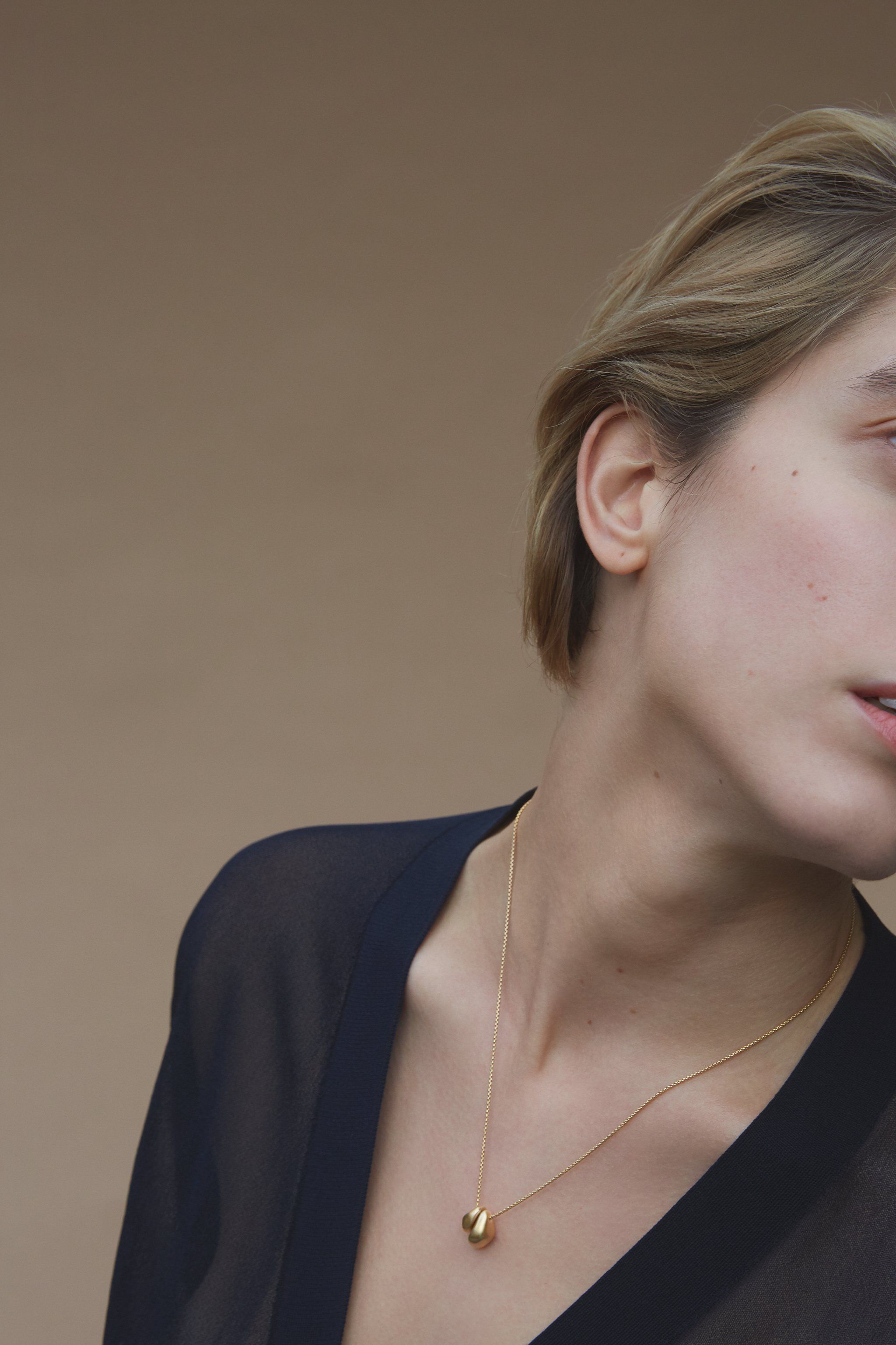 Model wearing ONOA necklace, a handmade ethical jewelry piece in recycled gold, showcasing timeless design.