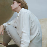 Model wearing a white shirt and light pants, showcasing the handmade ONOA ring in an artistic setting.
