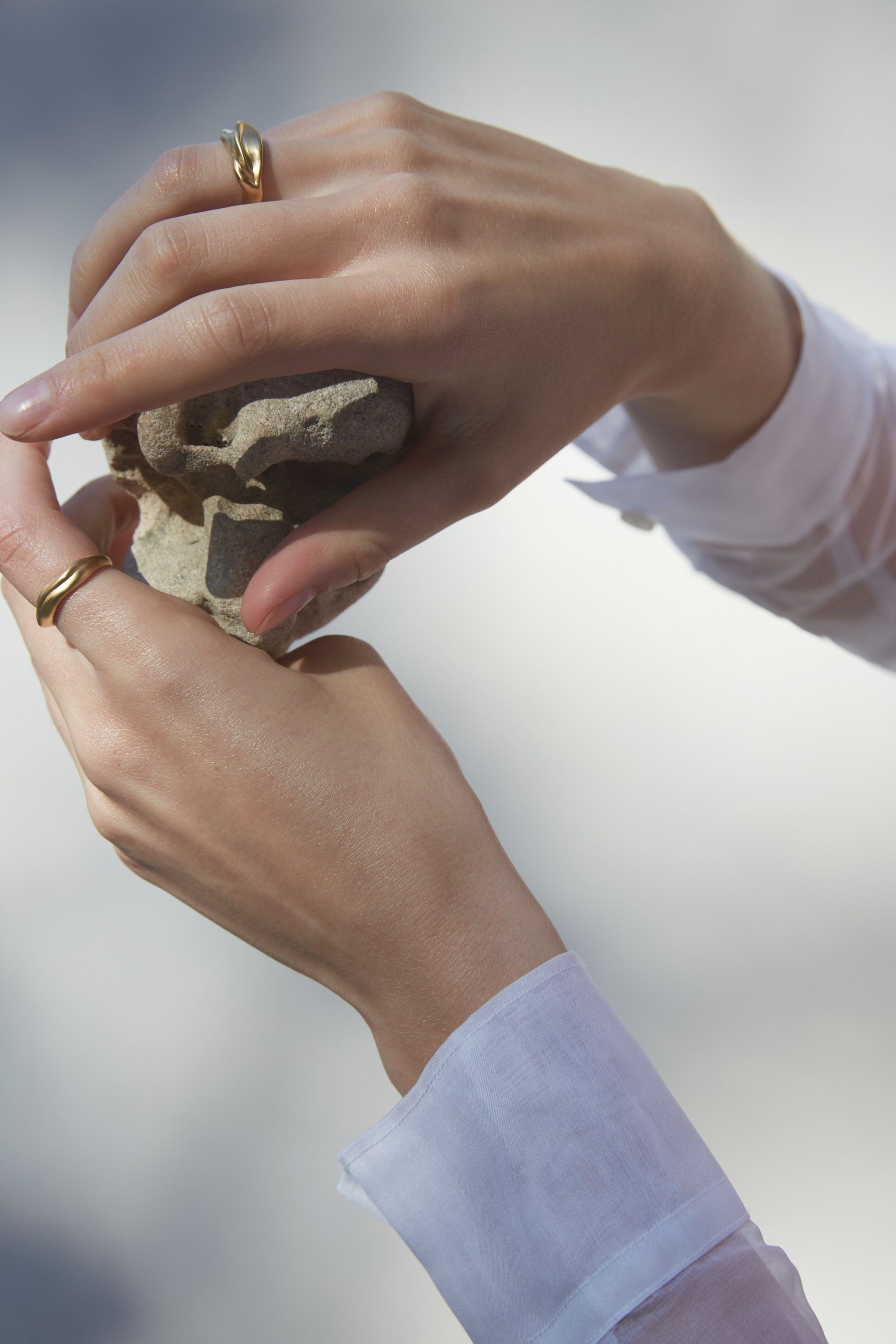 Hands holding a stone, adorned with YERERA big ring, showcasing ethical and sustainable jewelry craftsmanship.