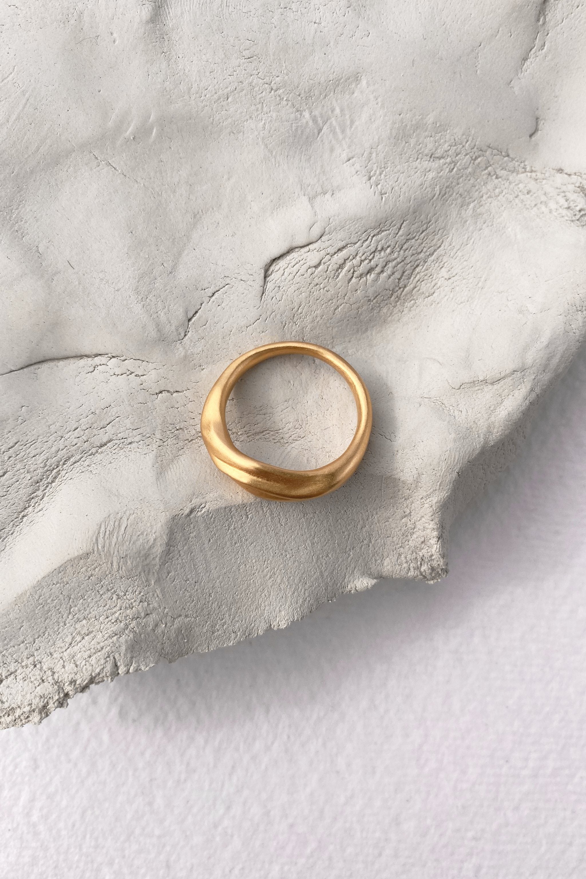 YERERA small ring in 18k gold-plated brass on textured surface, showcasing ethical handmade sustainable jewelry.