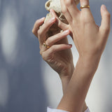 Hands holding a natural stone wearing YERERA small ring, showcasing ethical handmade jewelry in gold-plated brass.