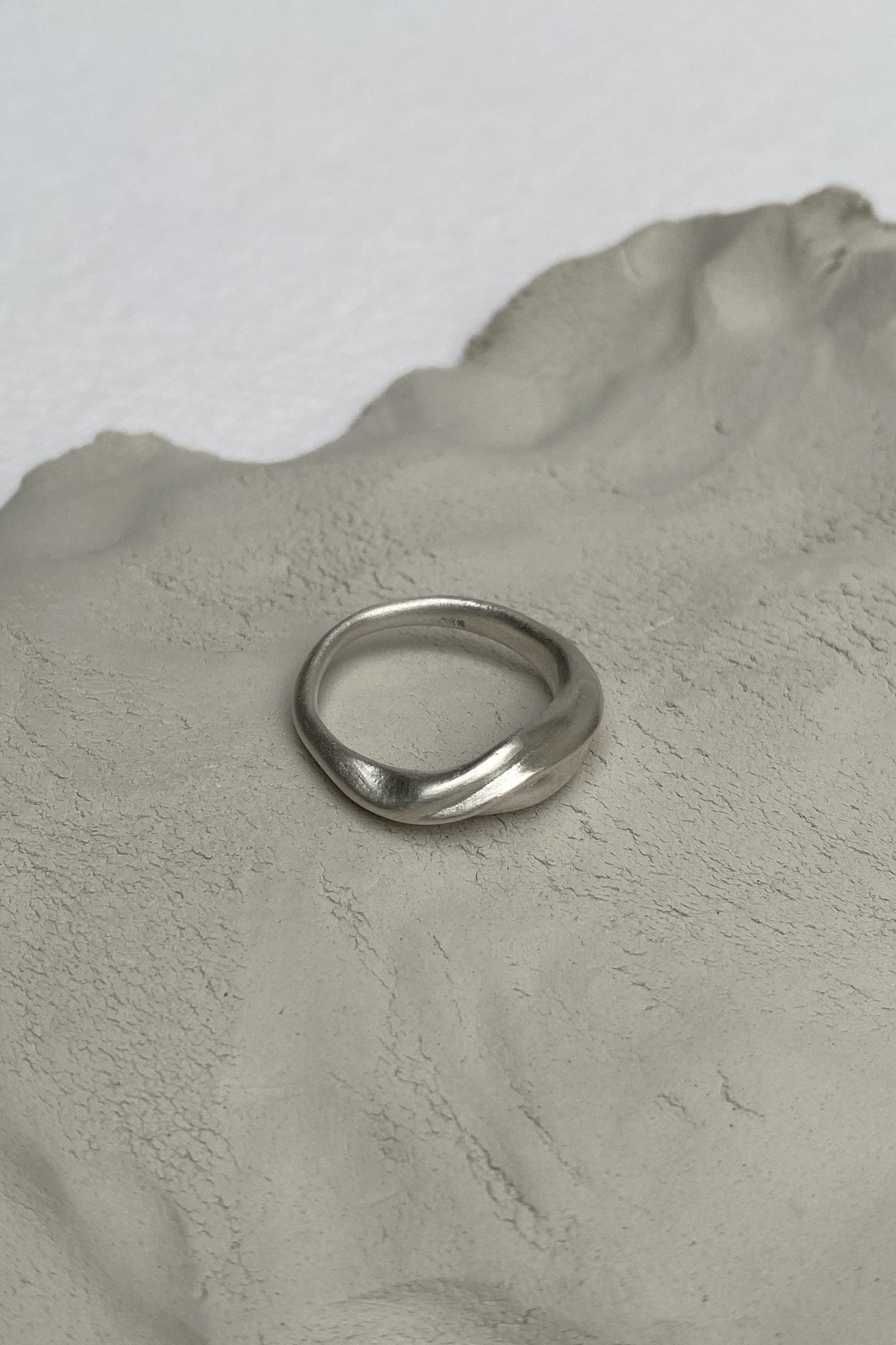 YERERA small handmade ring in recycled silver on textured clay surface, highlighting ethical and sustainable jewelry.