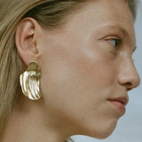 Handmade AJUN earrings in recycled gold, showcasing a matte finish on a model's ear, highlighting ethical jewelry design.