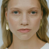 Model showcasing AJUN earrings, handmade ethical jewelry crafted from recycled gold or silver, highlighting sustainable fashion.