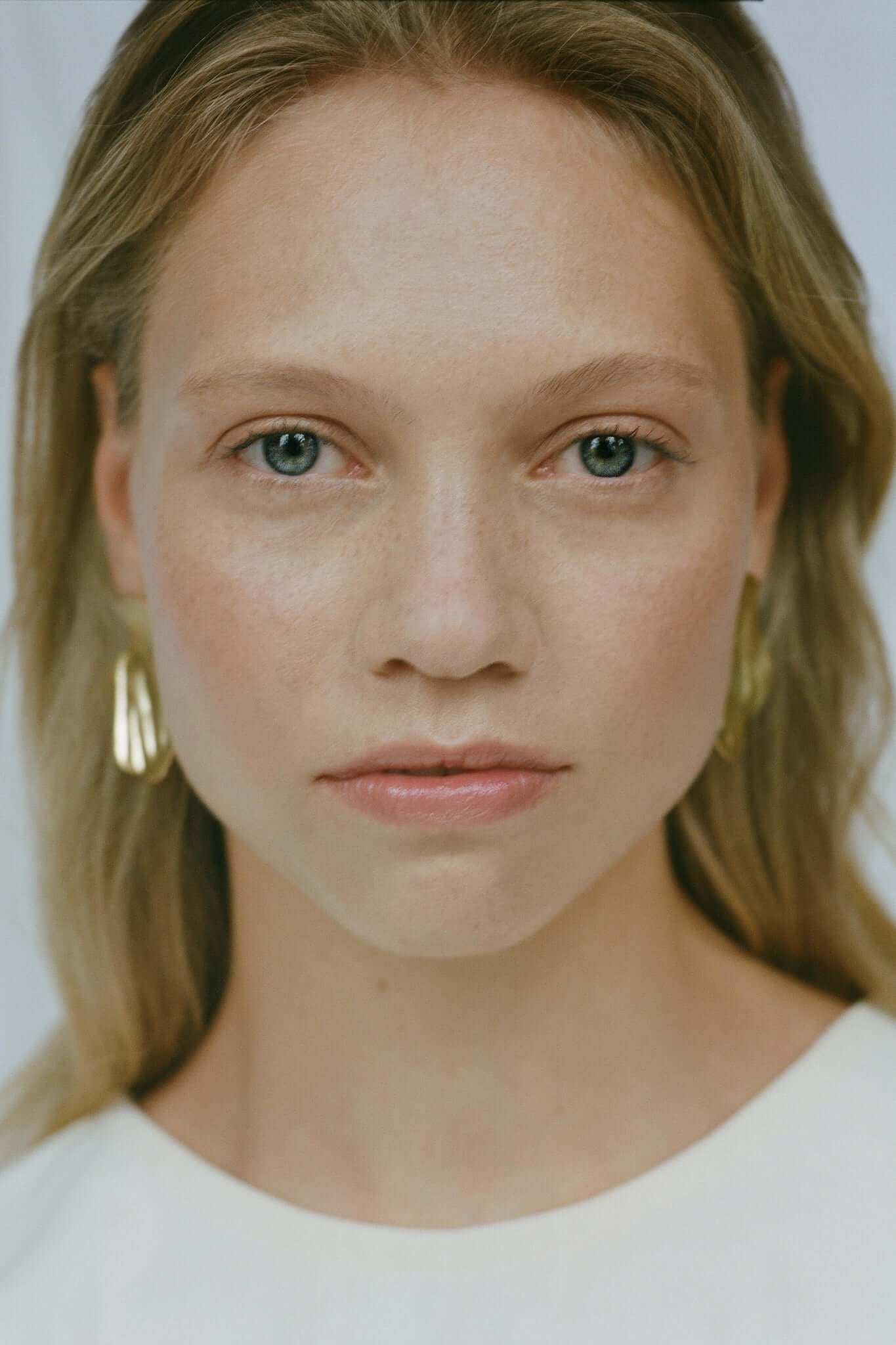 Model showcasing AJUN earrings, handmade ethical jewelry crafted from recycled gold or silver, highlighting sustainable fashion.