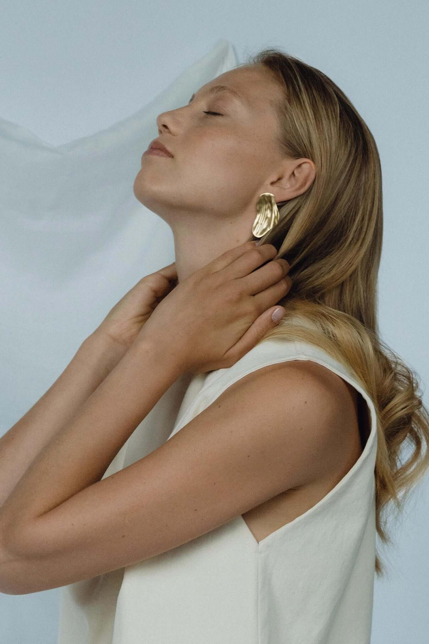 Model wearing AJUN 18k gold-plated recycled silver earrings, showcasing elegant ethical jewelry and sustainable craftsmanship.