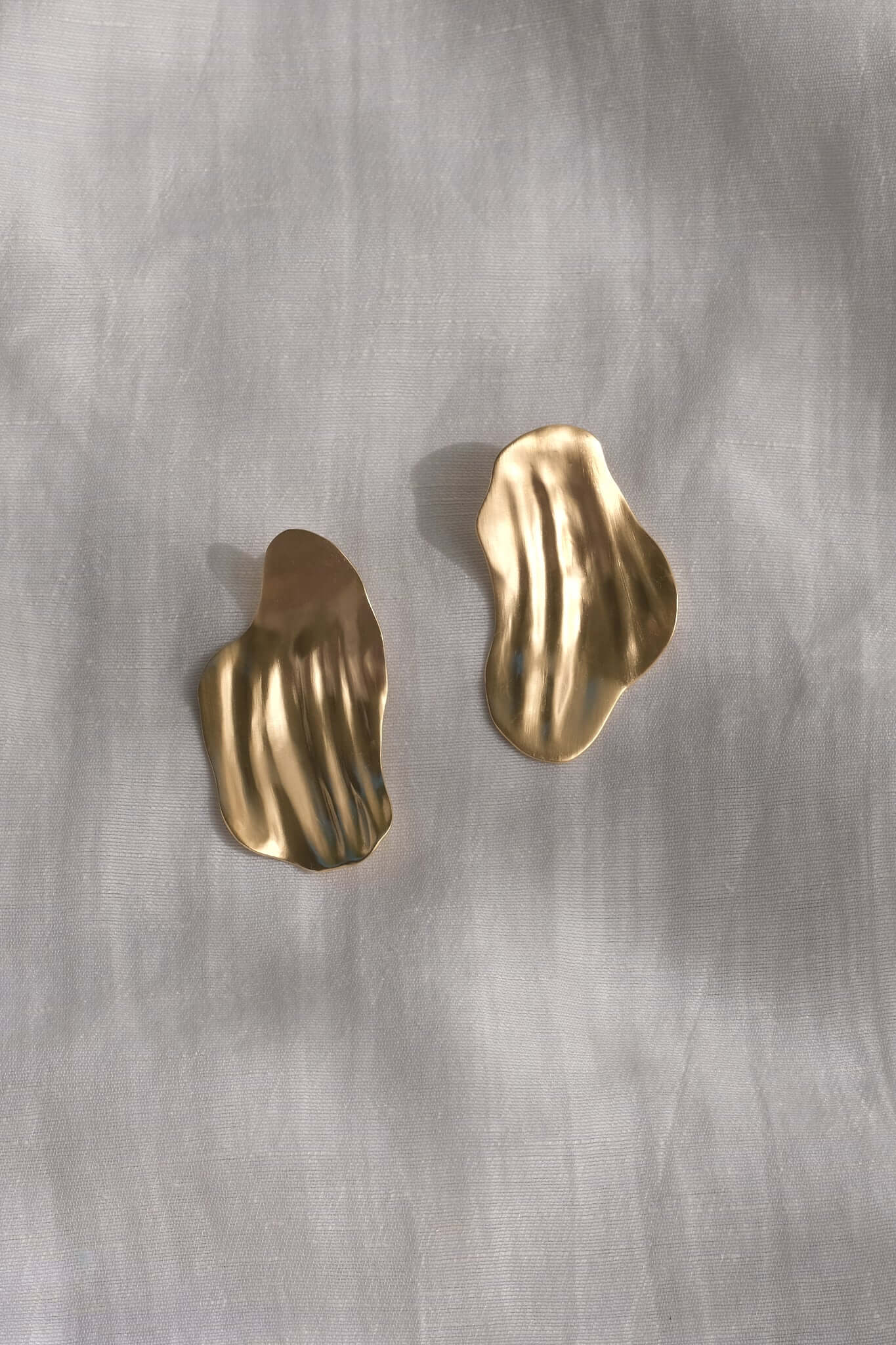Elegant handmade AJUN earrings in recycled gold, featuring a textured, wavy design, symbolizing sustainable jewelry.