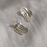 AJUN earrings in recycled silver with a matte surface, showcasing elegant, wavy designs for ethical jewelry lovers.
