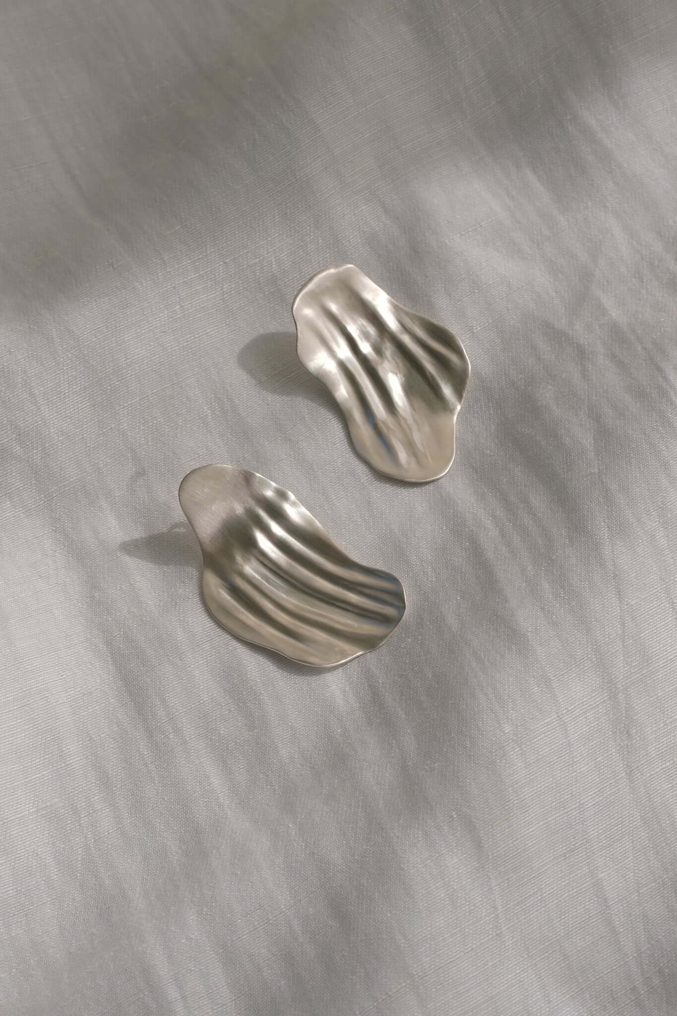 AJUN earrings in recycled silver with a matte surface, showcasing elegant, wavy designs for ethical jewelry lovers.