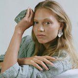 Model showcasing AJUN handmade earrings made from recycled silver, promoting sustainable and ethical jewelry.
