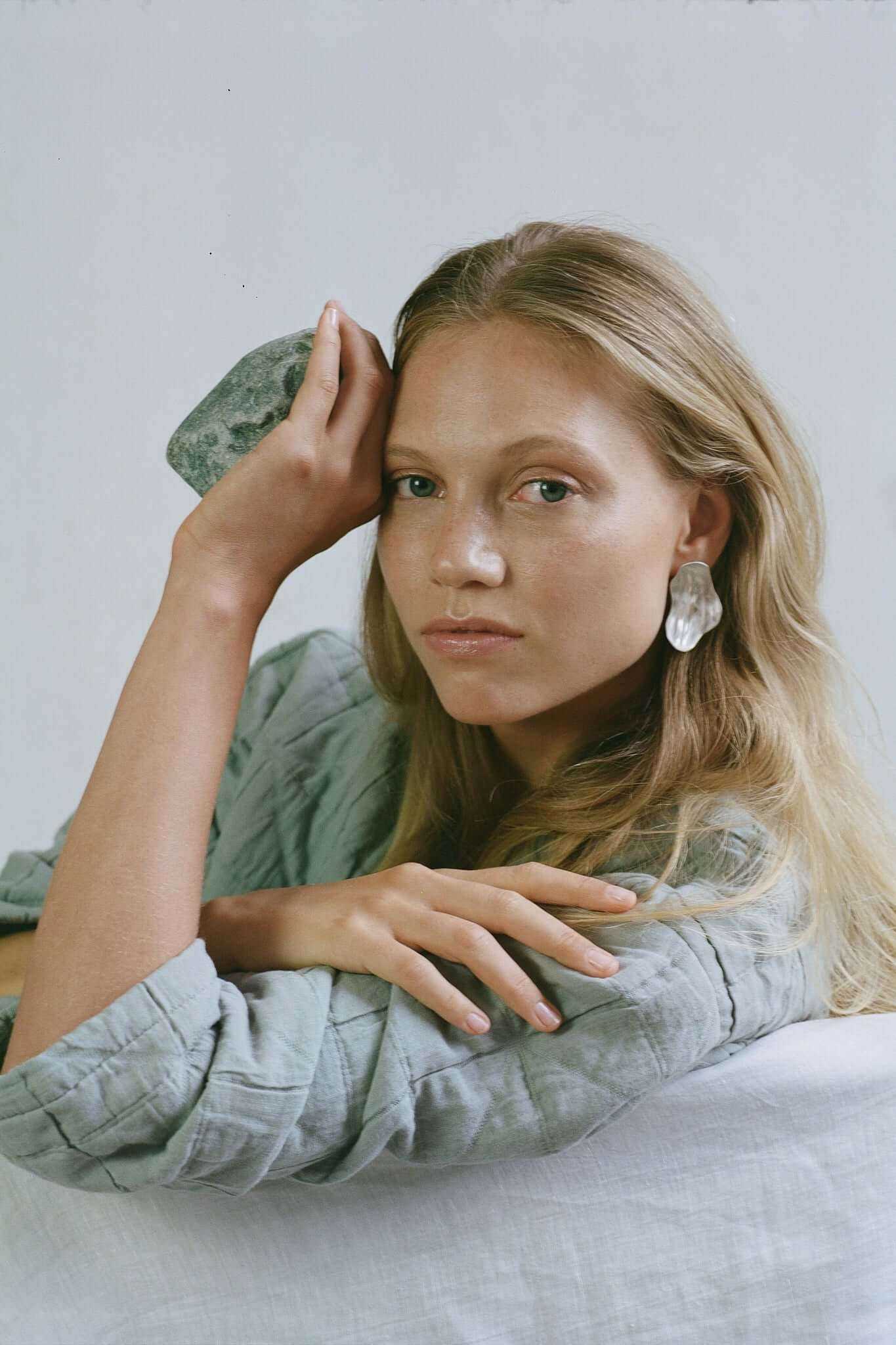 Model showcasing AJUN handmade earrings made from recycled silver, promoting sustainable and ethical jewelry.