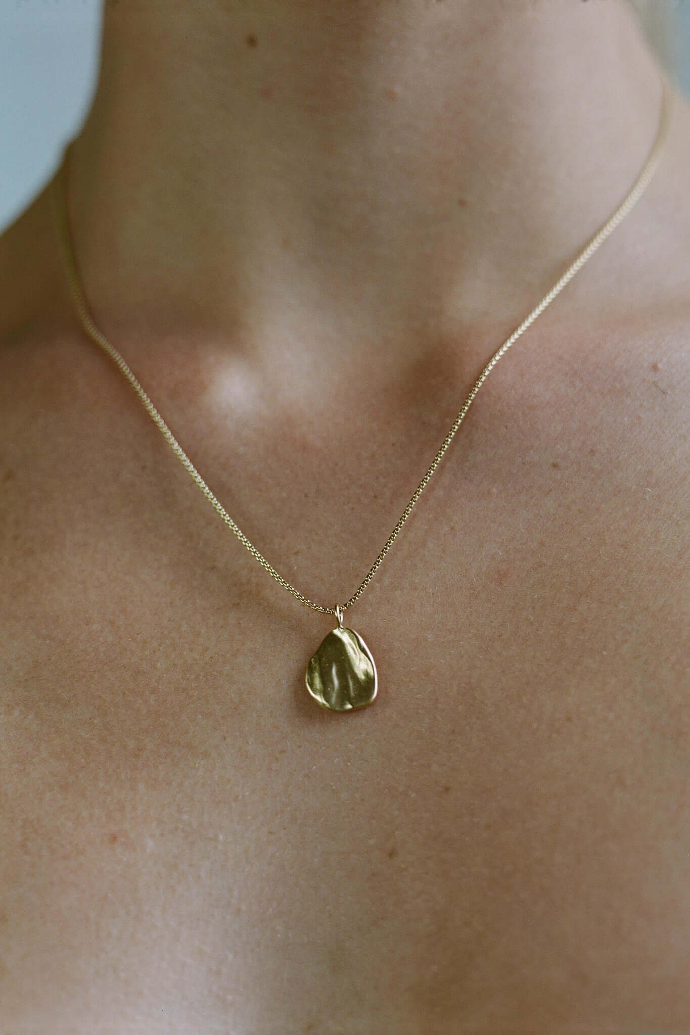 AJUN necklace in 18k gold plate, showcasing ethical, handmade jewelry on a model's neck.