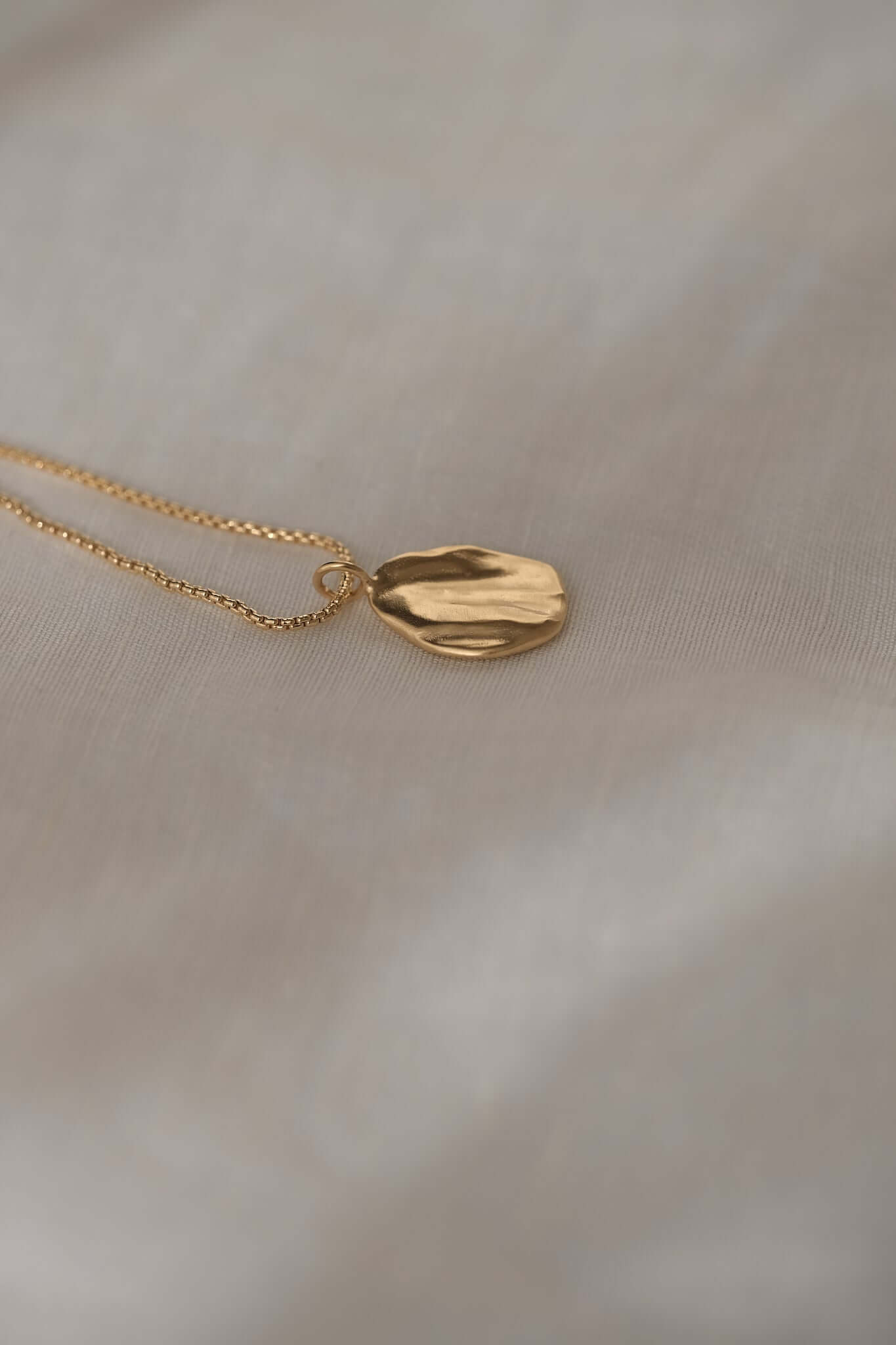 AJUN handmade necklace with a recycled gold pendant on a delicate chain, showcasing sustainable ethical jewelry.