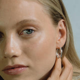 Close-up of a woman wearing LUMI big handmade earrings made from recycled silver, showcasing ethical jewelry design.