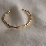 LUMI cuff made of 18k gold-plated recycled silver, showcasing a handmade, ethical design on a soft fabric background.