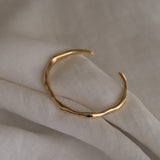 LUMI cuff in 18k gold-plated recycled silver, showcasing sustainable and handmade ethical jewelry on soft fabric.