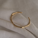 Handcrafted 18k recycled gold cuff bracelet on light fabric, designed in Basel, Switzerland.