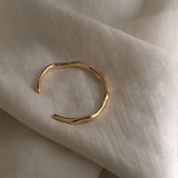 LUMI cuff bracelet in 18k gold-plated recycled silver resting on soft fabric, showcasing sustainable handmade ethical jewelry.