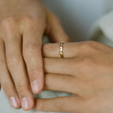 Close-up of hands wearing a LUMI ring, showcasing its ethical handmade design in recycled gold.