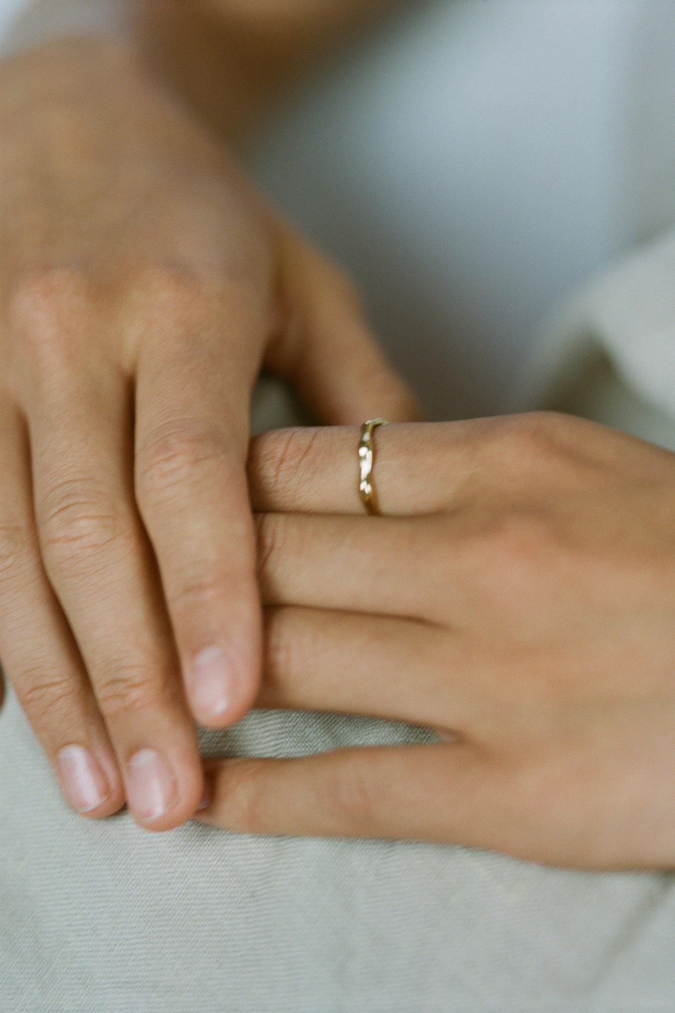 Close-up of hands wearing a LUMI ring, showcasing its ethical handmade design in recycled gold.