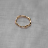 LUMI ring in 18k recycled gold, showcasing its unique, handmade design on a soft fabric background.