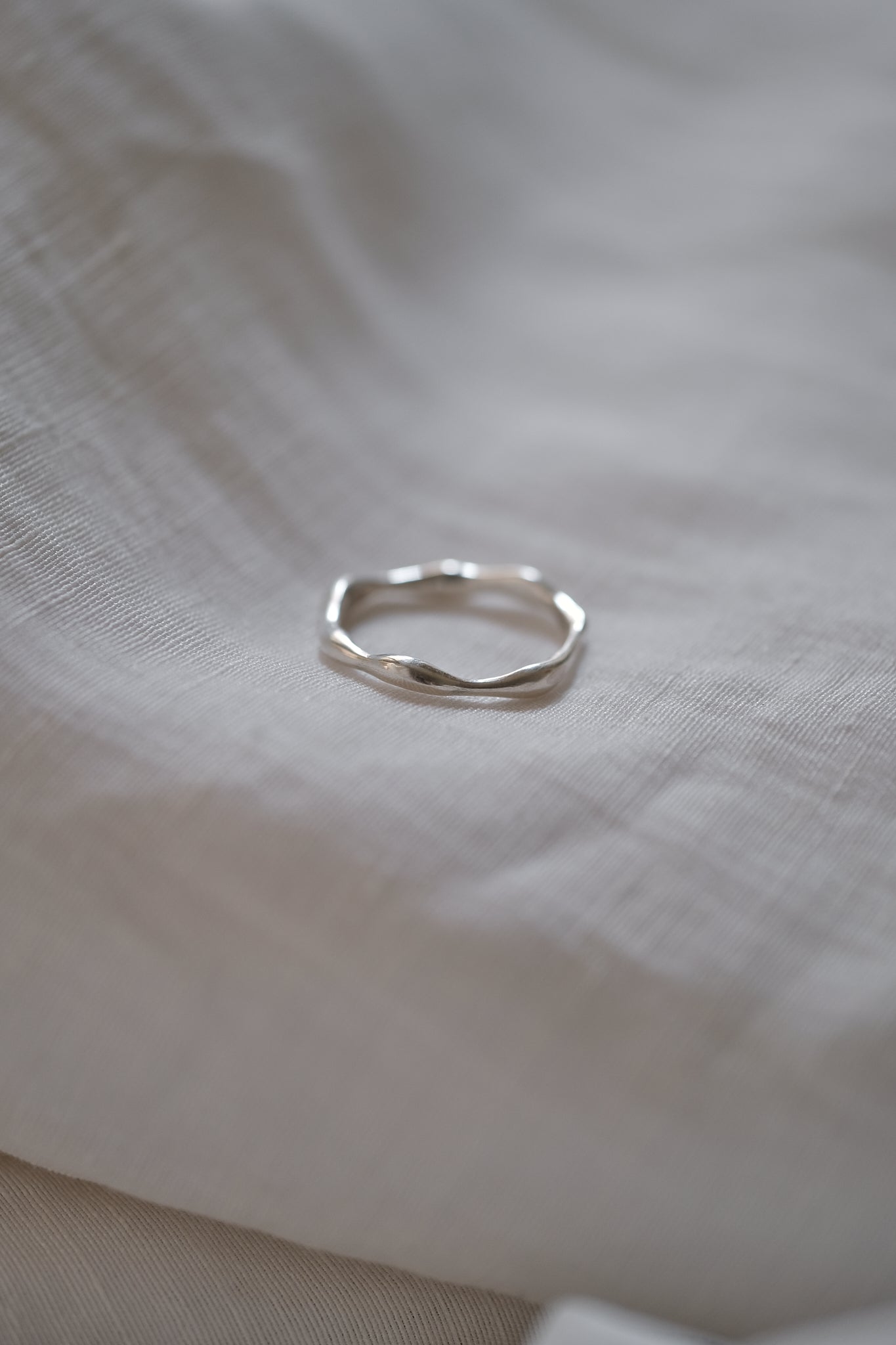 Handmade LUMI ring in recycled silver resting on soft fabric, showcasing ethical jewelry design and sustainable craftsmanship.